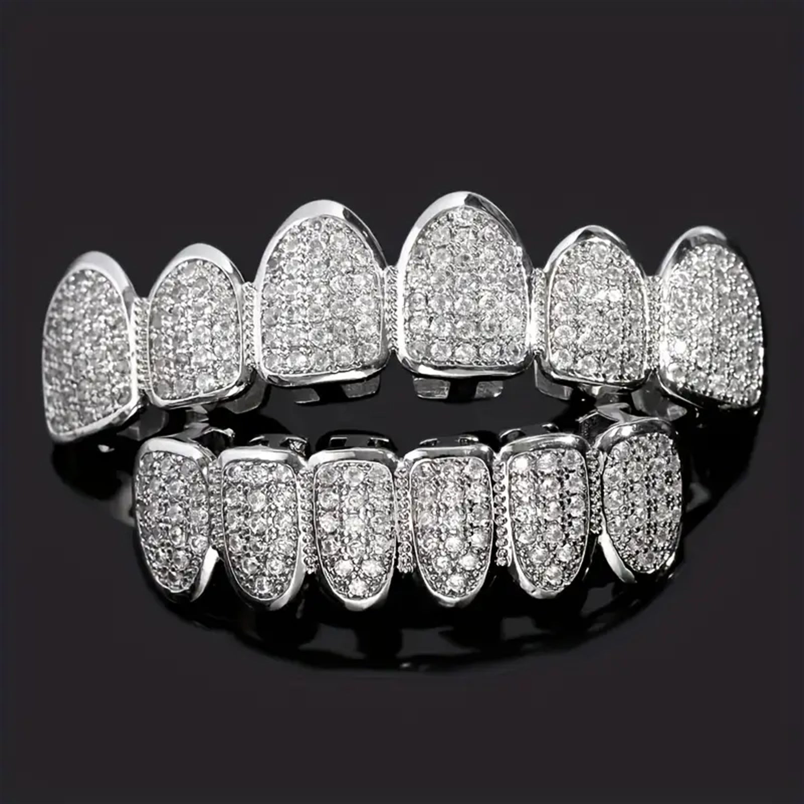 Close-up of a person wearing full silver CZ grillz on top and bottom teeth, with product flats showing both silver and gold colorways below