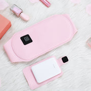 Flat lay of pink heating belt with power button and USB charging cable, showing product design and components