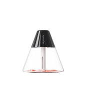 Woman holding open magazine next to active Schuyler Mist humidifier emitting fine mist; minimalist home setting with natural light