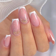 Manicured hand displaying French gel nails with soft pink base, white tips, and scattered gold glitter accent