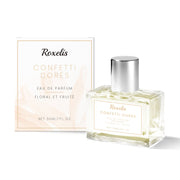 Roxelis Confetti Dorés eau de parfum bottle with silver cap next to cream and gold branded box packaging