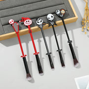 Five Nightmare Before Christmas makeup brushes laid flat on a grey surface and wooden tray, showing all 5 designs in red and black