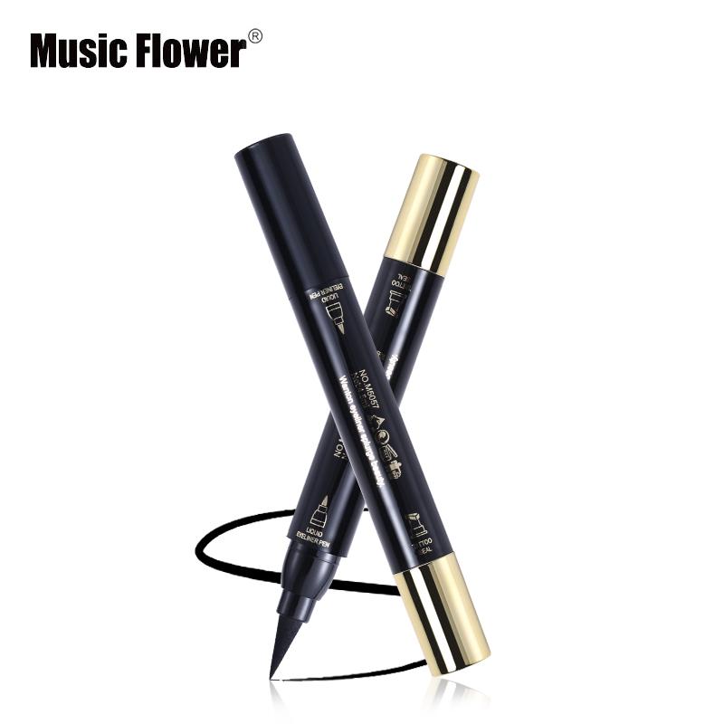 Two dual-ended eyeliner pens in black with gold-tone caps crossed artistically with drawn eyeliner strokes