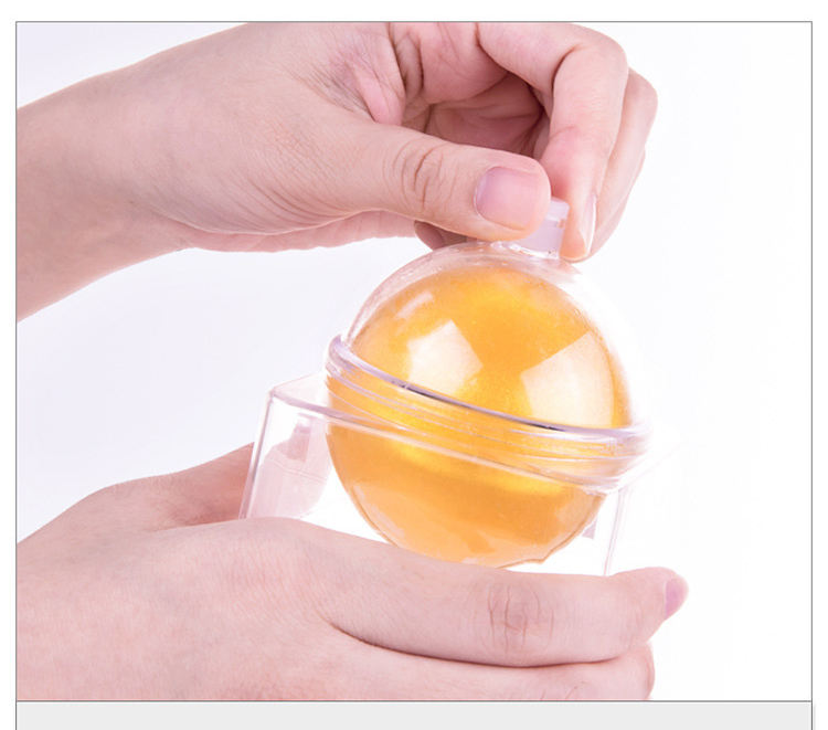 Transparent acrylic dome containing golden crystal jelly sphere against cream background with finger touch point