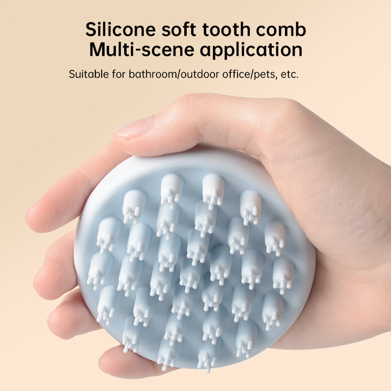 Hand holding blue silicone scalp massage brush with soft rounded teeth, demonstrating compact size and portability