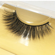 Close-up of dramatic mink false eyelashes on golden surface displaying full volume and feathered fiber detail