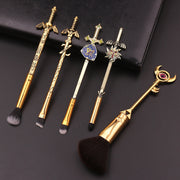 Five Legend of Zelda-themed makeup brushes laid out on a dark leather surface showing the full set including Master Sword fan brush and Eye of Truth staff brush