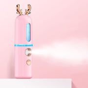 Pink nano hydrating sprayer with gold reindeer ears on pastel pink background showing mist function