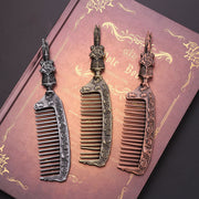 Three Harry Potter Hogwarts-themed antique metal combs in bronze, gold-bronze, and copper laid on a purple Harry Potter-style notebook with gold embossing