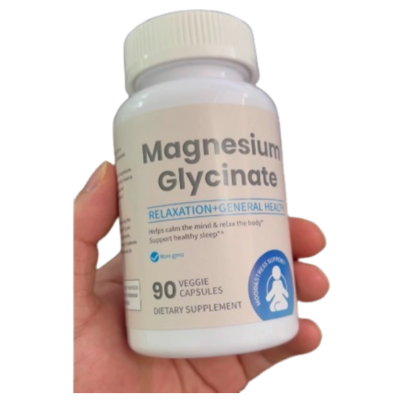 Hand holding cream-colored plastic bottle of Magnesium Glycinate supplement with white ribbed cap