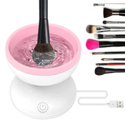 Automatic makeup brush cleaner in use with black brush being cleaned in pink water-filled basin