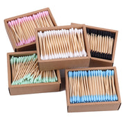 Exploded view of five colorful cotton swab boxes arranged dynamically showing pink, white, black, mint green, and blue options
