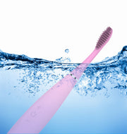 Pink silicone toothbrush half-submerged in splashing water