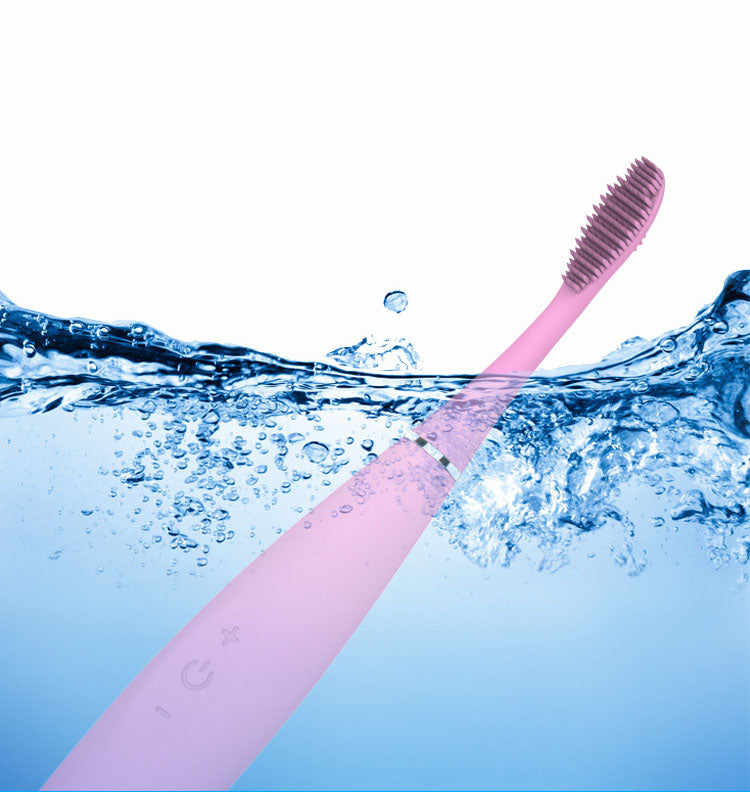 Pink silicone toothbrush half-submerged in splashing water