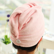 Woman wearing pink hair drying cap with turban-style wrap and button closure, styled at crown