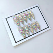 Full set of sparkly almond-shaped press-on nails with iridescent AB crystal rhinestones displayed in white framed presentation box