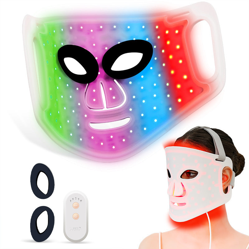 Vibrant LED light therapy mask with rainbow color gradient showing all light wavelengths active, featuring 98 glowing LED beads with black alien-style eye cutouts and pink nose contour, displayed with wireless remote control and replacement ear loops