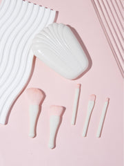 Complete 5-piece brush set with shell case arranged against pink backdrop with wavy white elements