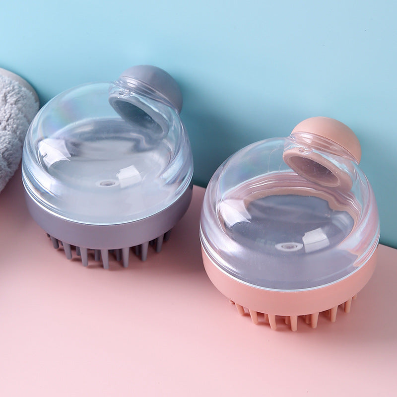 Two scalp massage shampoo brushes in grey and pink displayed side by side on a pastel background showing their transparent dome reservoirs and silicone bristles