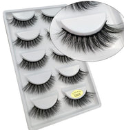 Five pairs of black 3D mink false eyelashes arranged in clear plastic case with magnified close-up showing dense, feathery fiber detail