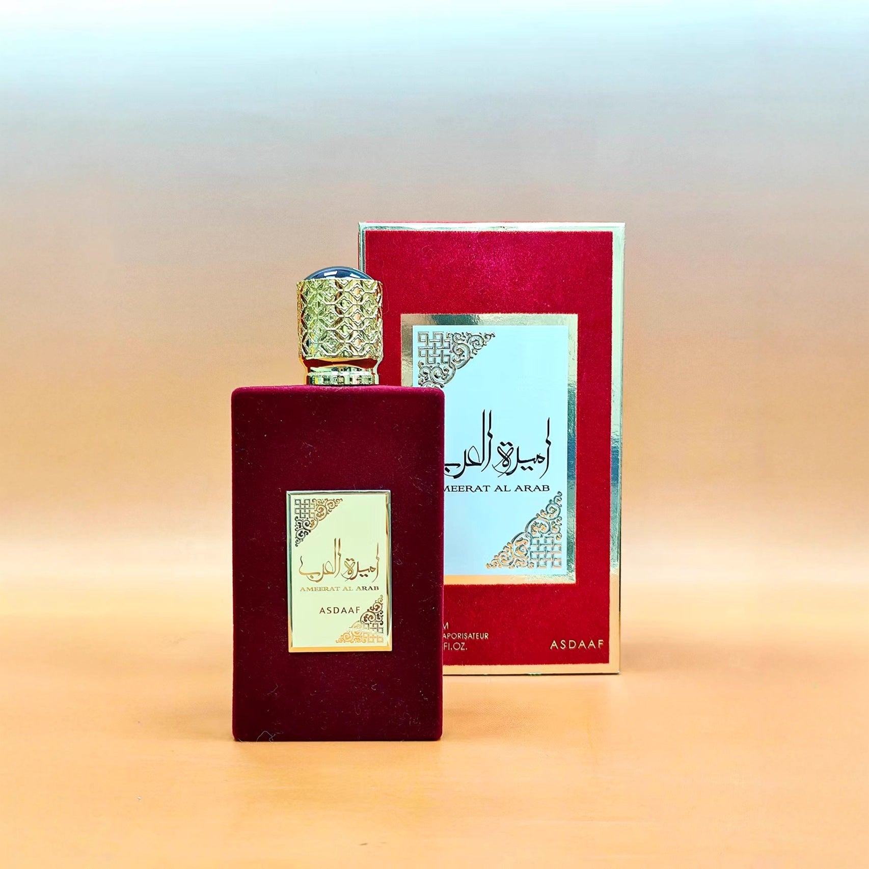 Deep burgundy bottle variant with gold-filigree cap and matching red outer box on warm desert-toned background
