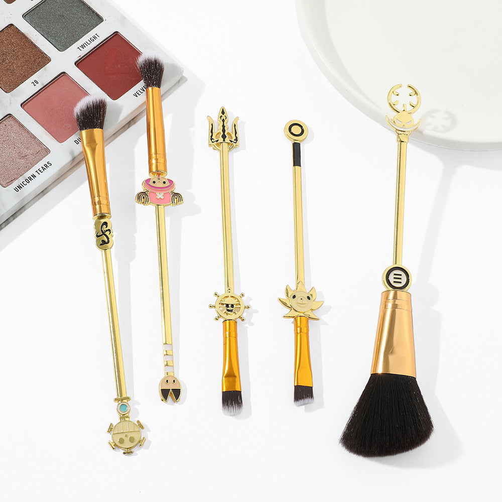 5 One Piece anime makeup brushes laid flat showing brush heads including large powder brush, eyeshadow brushes, and liner brush alongside eyeshadow palette
