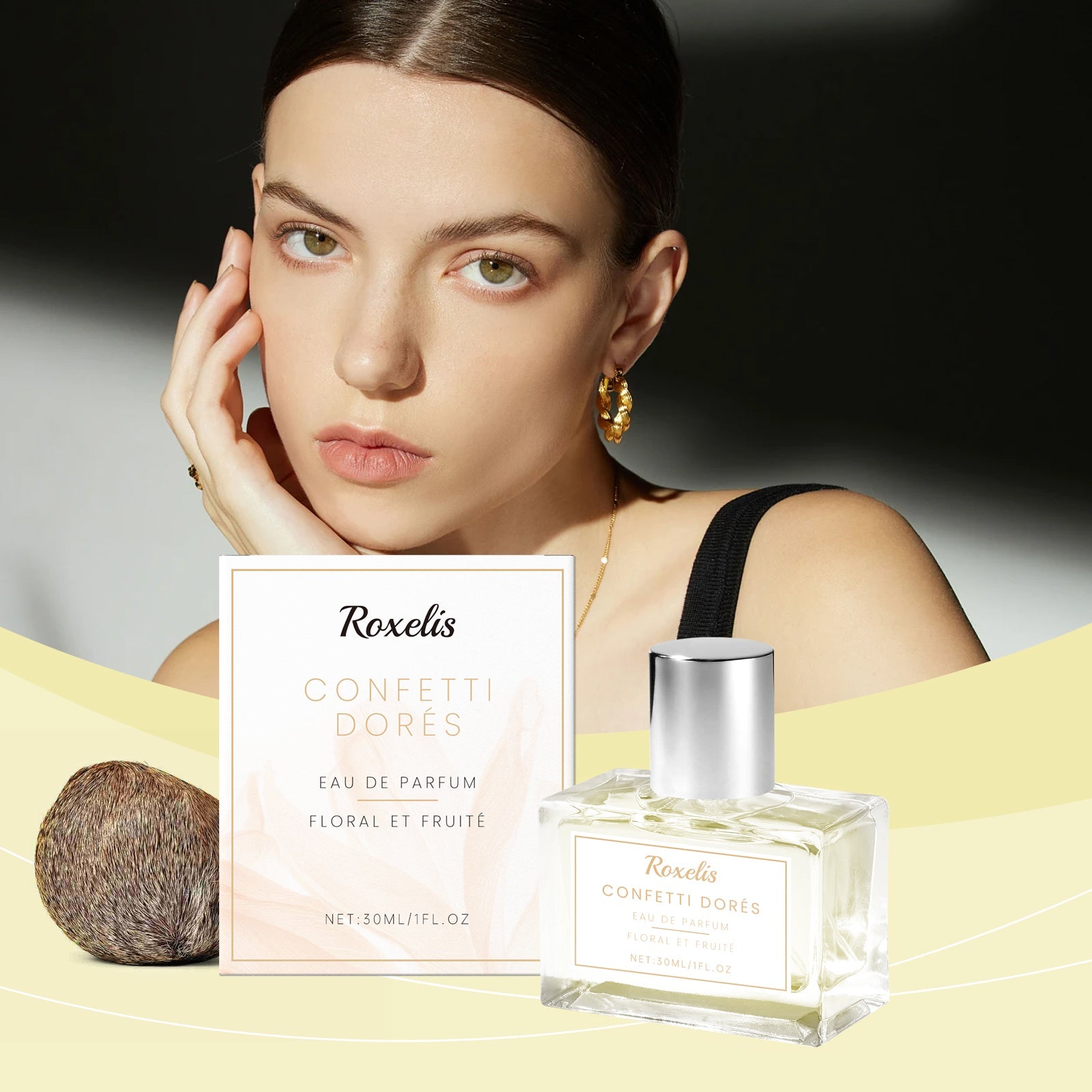 Woman wearing the fragrance with minimalist styling, product displayed on pastel yellow surface with dried rattan sphere