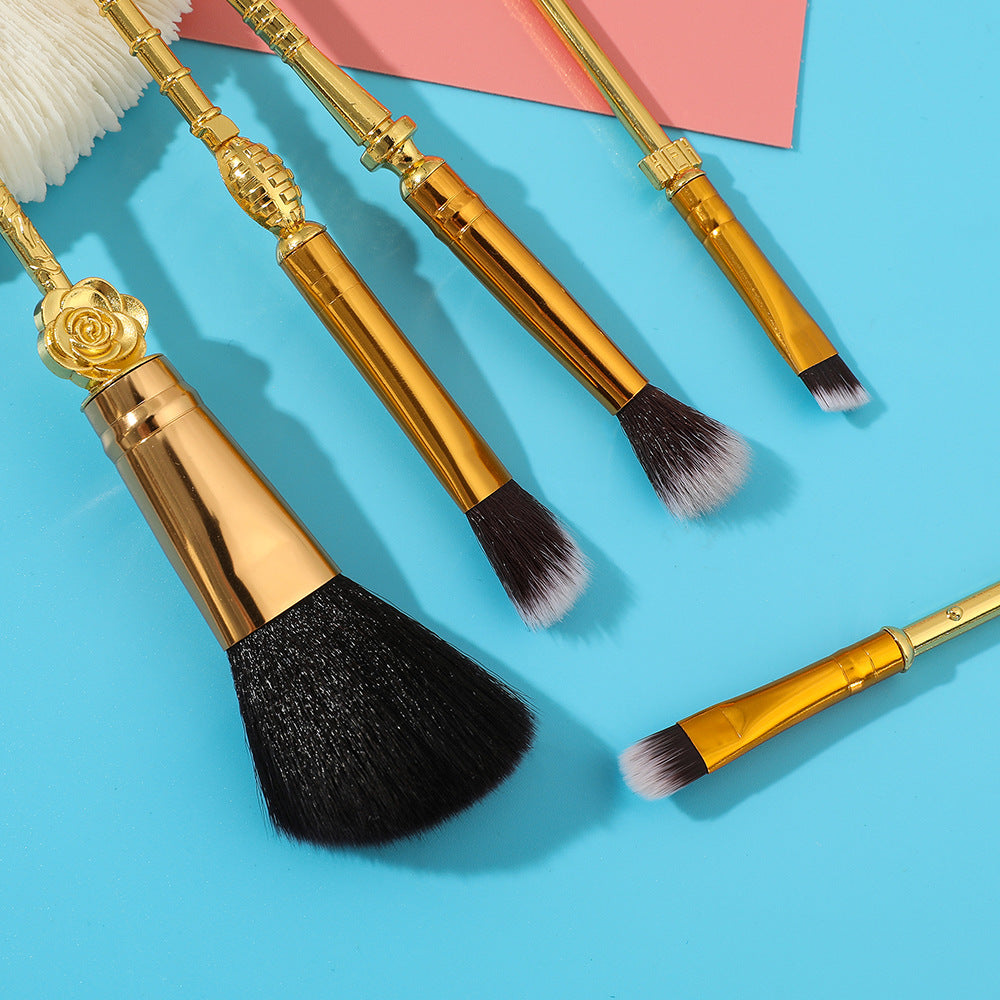 Five brush heads fanned out against a vintage notebook background showing bristle texture and gold ferrules