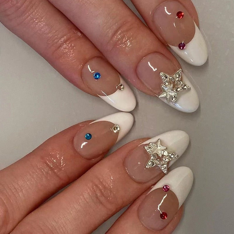 Duplicate close-up shot of decorated French nails with dimensional stars and jeweled accents