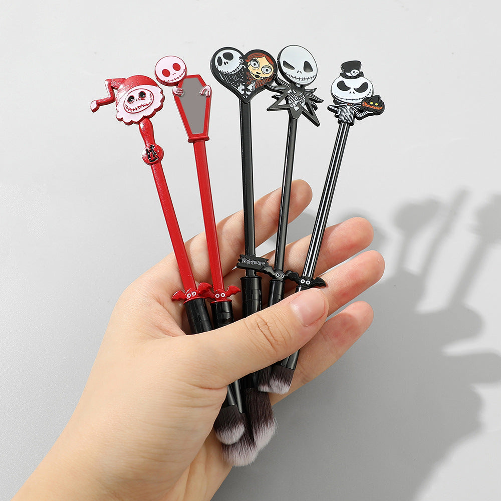 Hand holding all five character makeup brushes fanned out, showing size in relation to hand and detailed topper designs