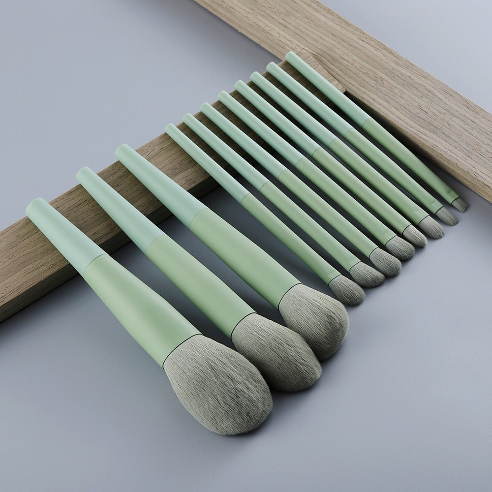 Close-up of the largest powder brush and medium brushes leaning against a wooden block on a grey background