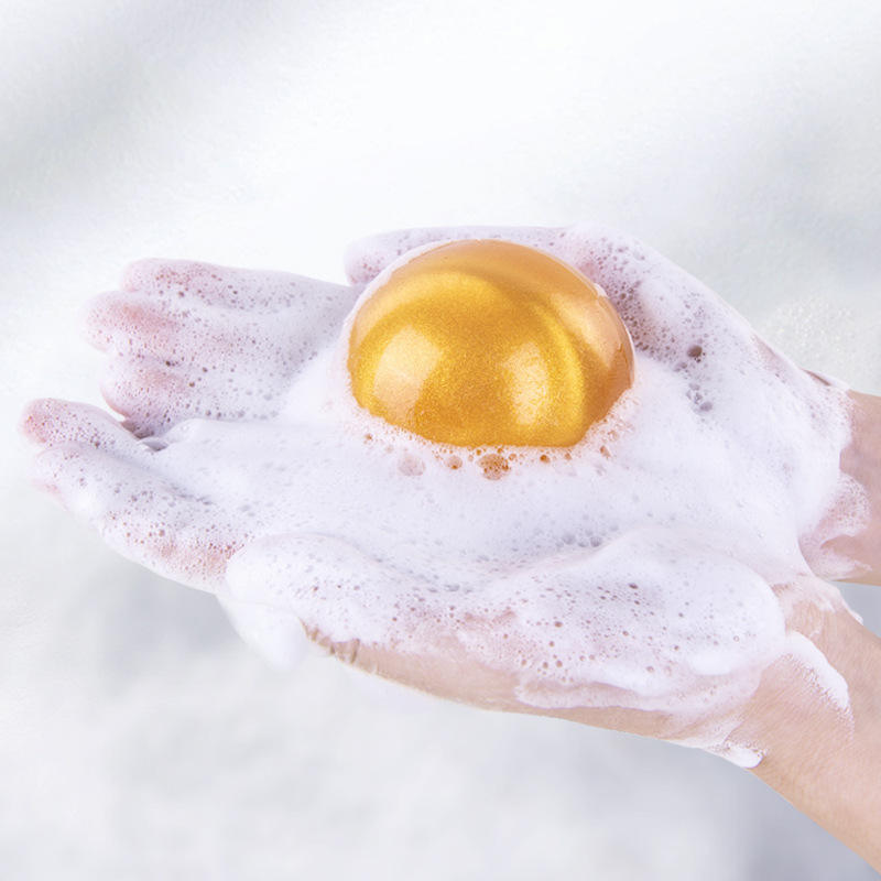 Hands holding gel ball nestled in white foaming lather with subtle pink and gold sparkle particles