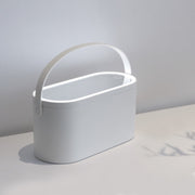 Hand touching the touch-control button on the LED mirror of an open blush-pink makeup case filled with cosmetics