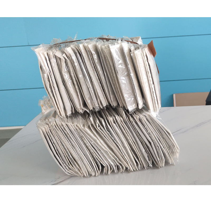 Stack of white heating sachets displayed against blue background showing large bulk quantity