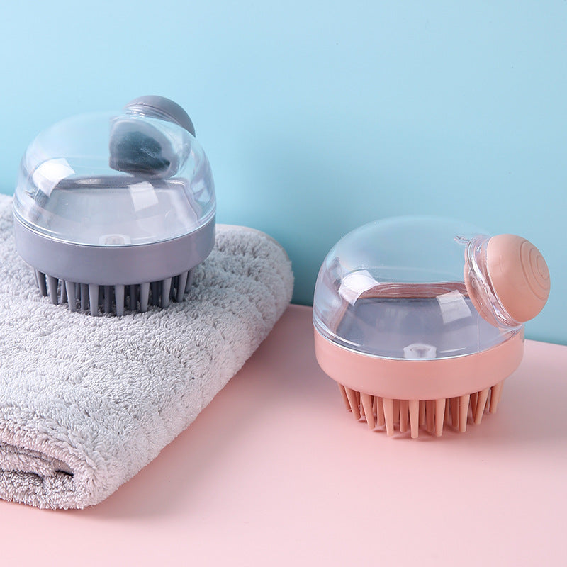 Hand holding pink shampoo brush upside down showing liquid dispensing through the central hole of the pink silicone bristles