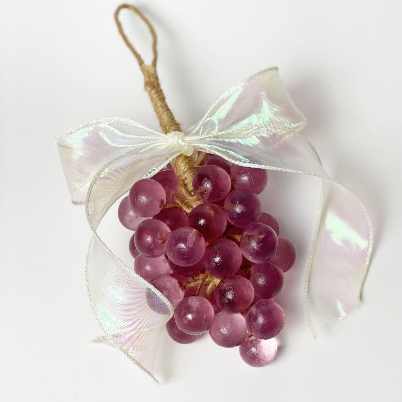 Three grape cluster ornaments held in hand showing three color options: pink, green, and burgundy