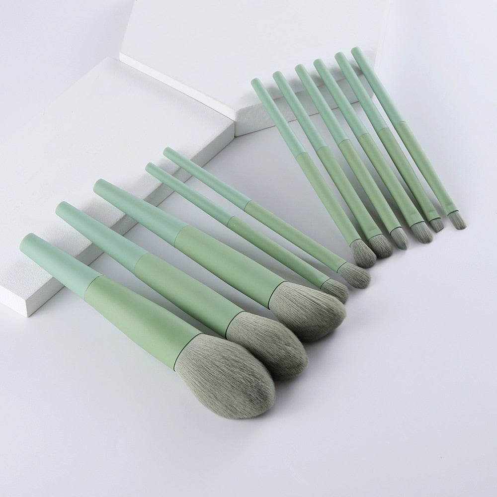 11 brushes laid flat in a row on a clean white surface, showing profile of each brush head shape