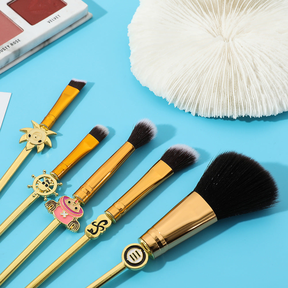 Close-up of brush heads and mid-handle character charms including Chopper, ship wheel, and sun figurehead against turquoise background