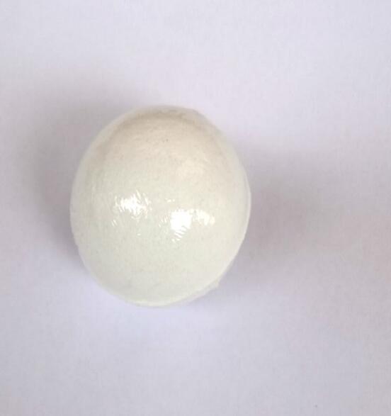 Close-up of a single white pearlescent bath bomb showing smooth glossy surface
