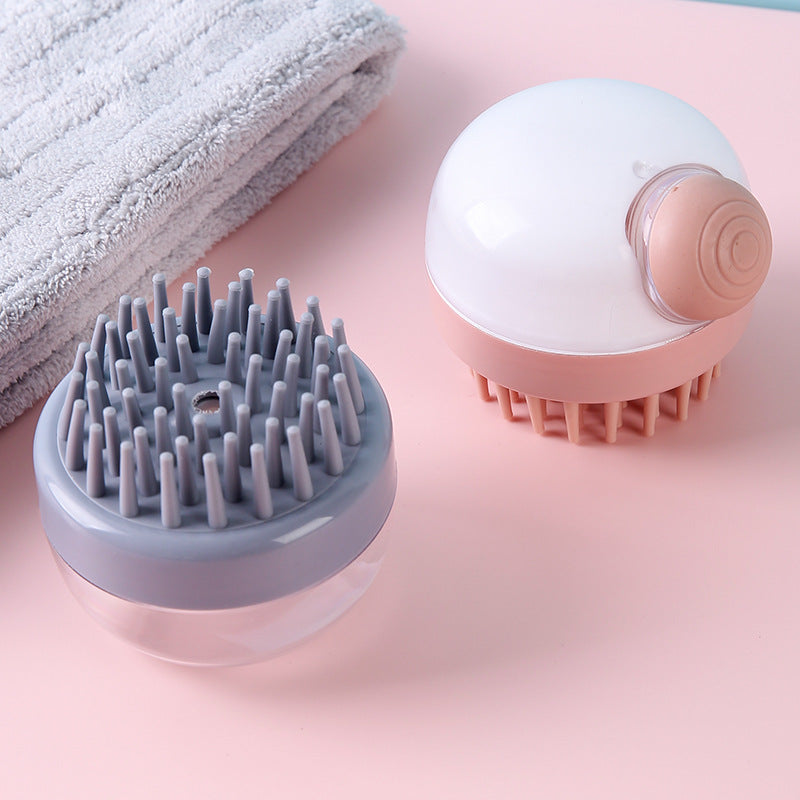 Grey and pink shampoo brushes placed next to a folded grey towel on a pastel surface