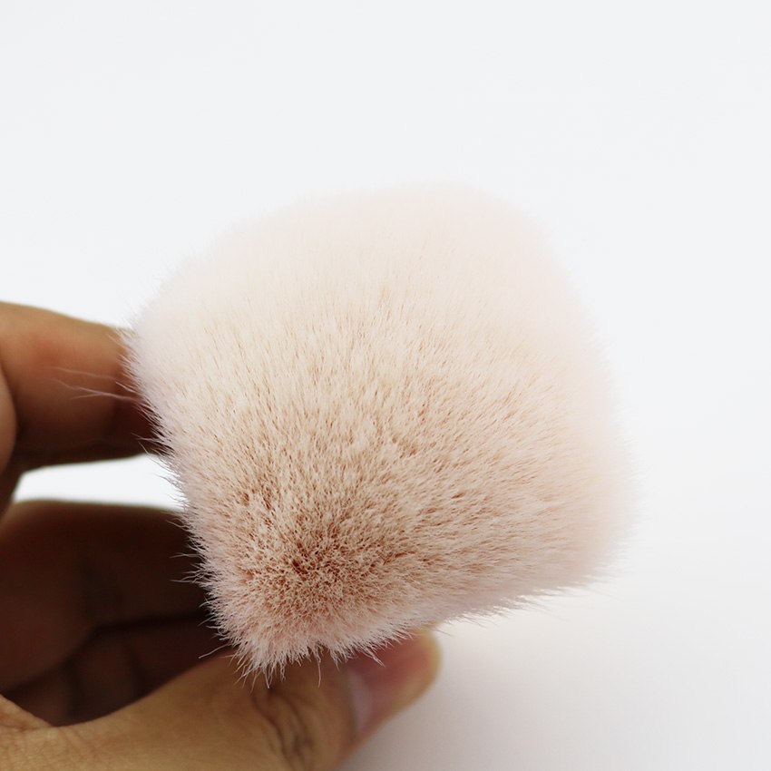 Extreme close-up of the blush-pink brush head bristle tips being gently pressed by fingers