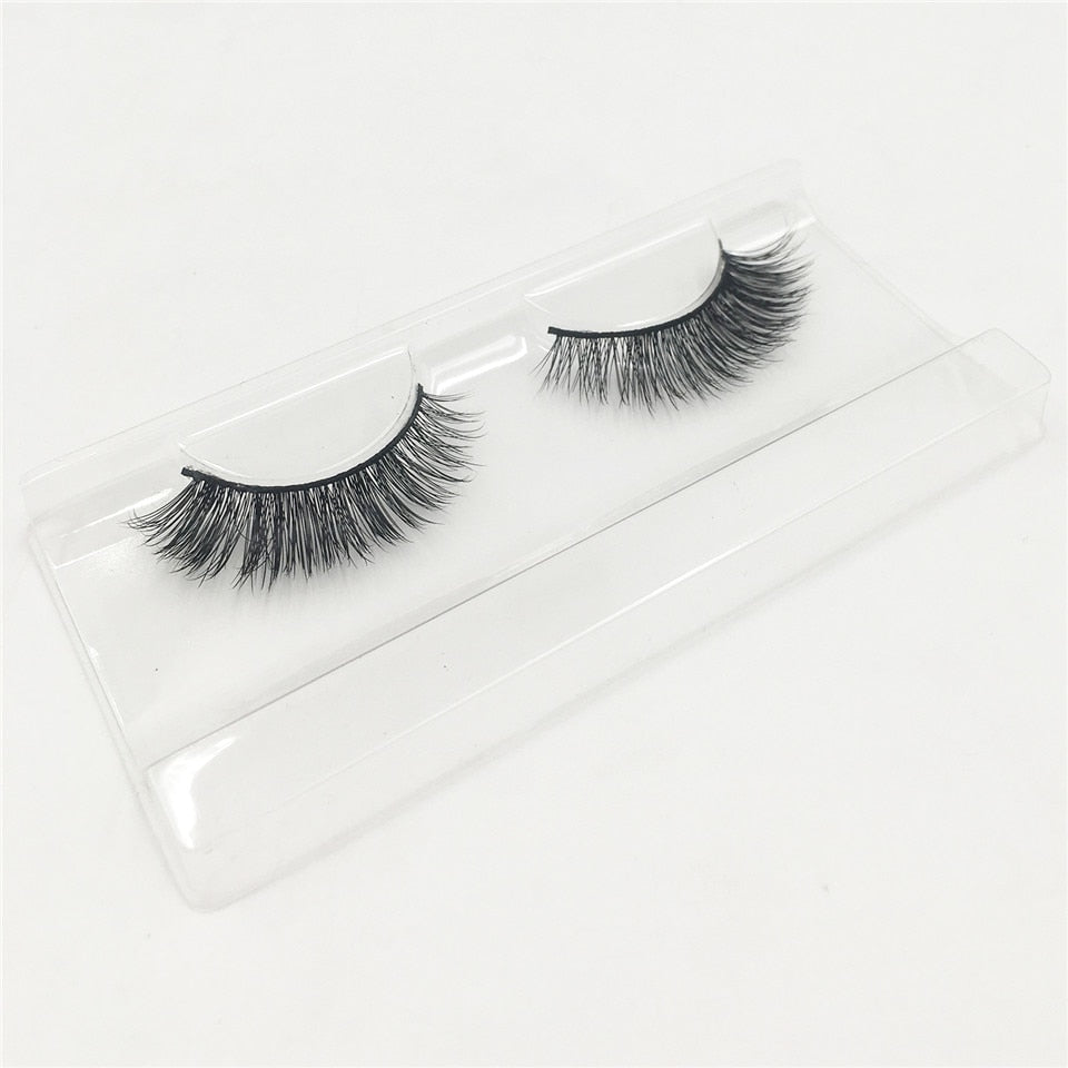 Pair of false eyelashes displayed on clear acrylic tray in protective packaging, showing final product presentation