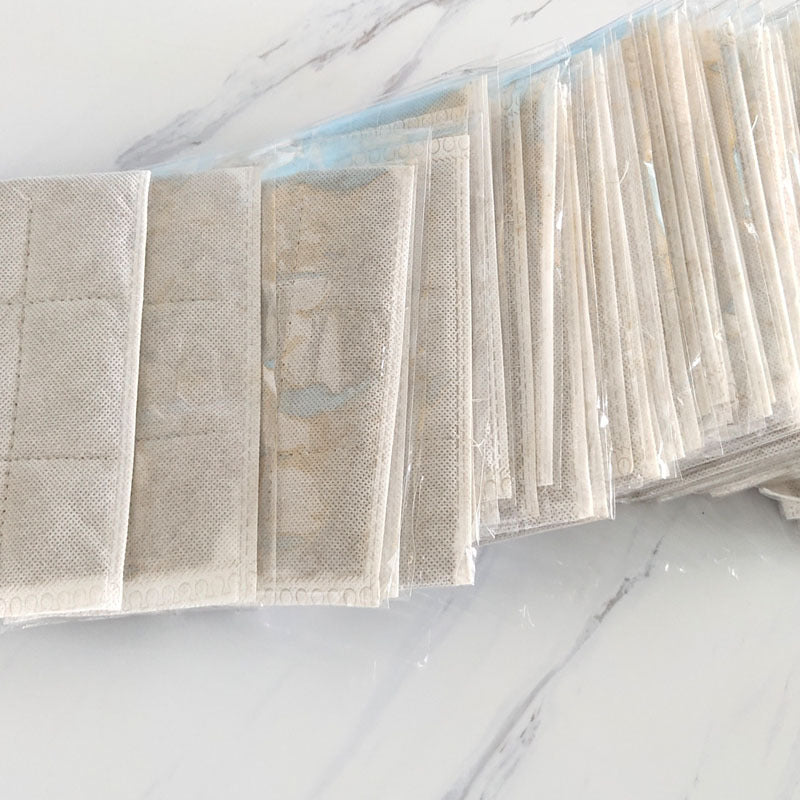 Two pale blue heating sachets in clear packaging showing lightweight non-woven fabric construction
