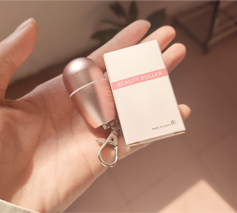Close-up of three volcanic stone rollers in rose gold casing, one held in hand against pink background