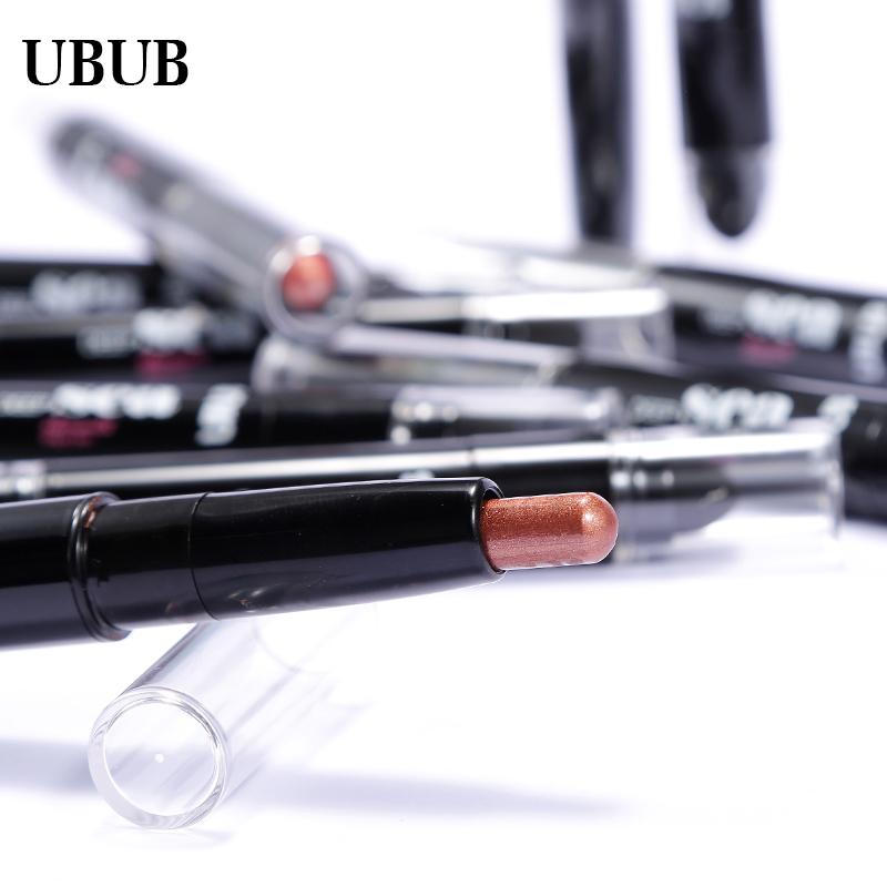 Close-up macro shot of copper-bronze eye pencil tip with nude shimmer and glitter swatches visible on white surface