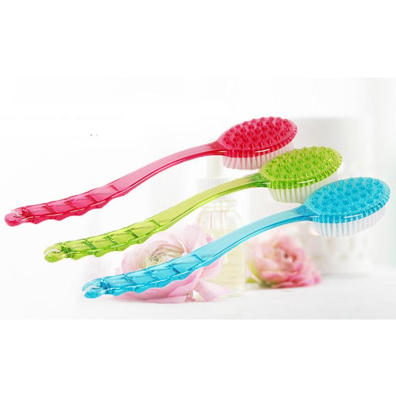 Three bath brushes in pink, green and blue colors arranged with decorative flowers